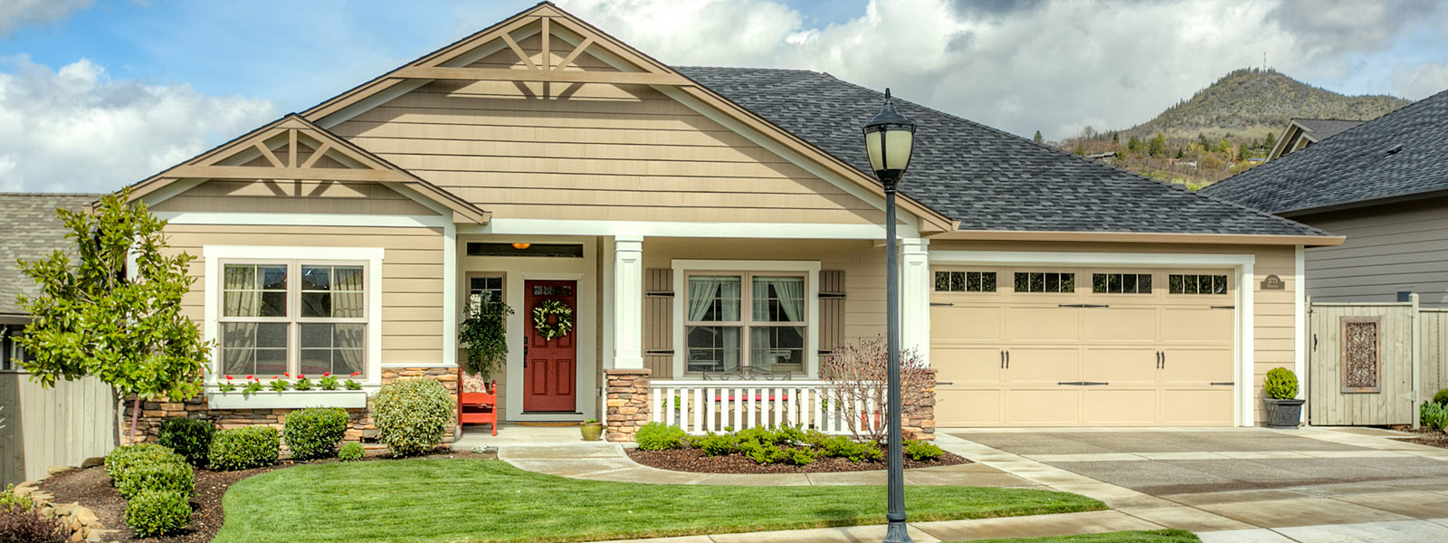 Craftsman home with a covered porch, landscaped lawn and mountain backdrop